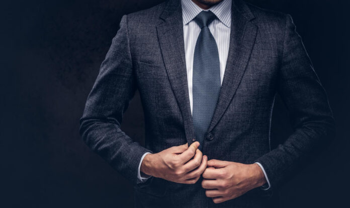 cropped portrait successful businessman buttoning his elegant suit isolated dark background